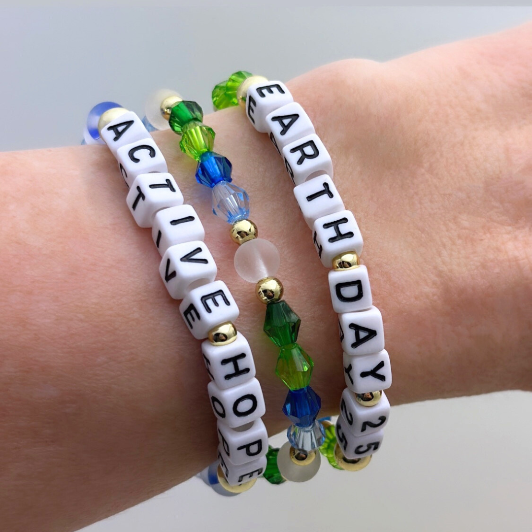 Earth Day 2025 Special Edition bracelet. Stack of 3 bracelets. Green, blue, white and gold beads. Letter beads that spell Earth Day 25 and Active Hope. Gold star logo bead to remind you that you shine.