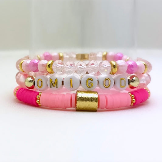 Broadway Stacks Omigod collection. 3 stretch bracelets included in Stack. Pinks, white and gold colored beads. Letter beads that spell Omigod.