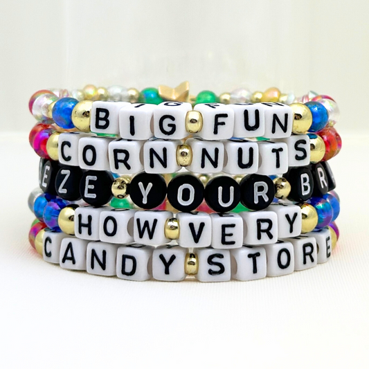 Broadway Stacks CORN NUTS Collection. 5 stretch bracelets included in Stack. Red, yellow, green, blue, black and gold colored beads. Letter beads that spell quotes. Gold star logo bead to remind you that you shine. Heathers the Musical fans.