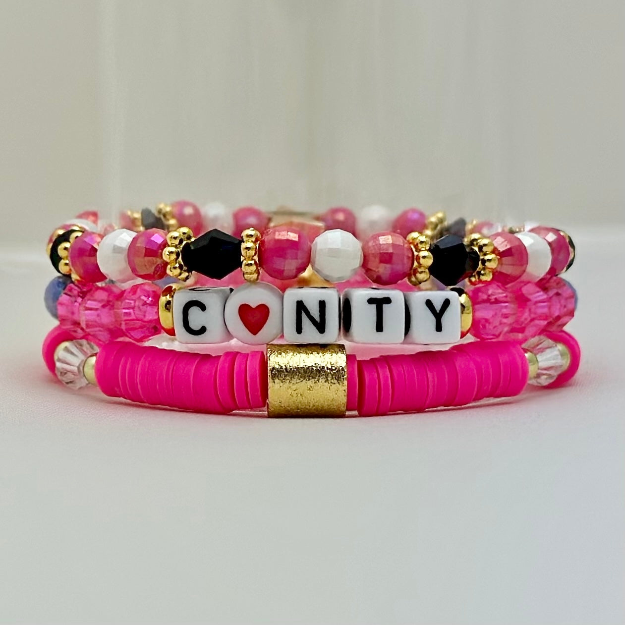 Broadway Stacks POTUS collection. 3 stretch bracelets included in Stack. Pinks, white, blue, golds and black colored beads. Letter beads that spell show quotes. Broadway Stacks gold star logo bead on back.