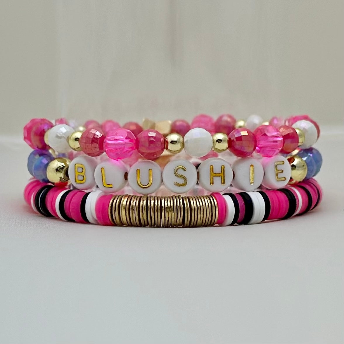 Broadway Stacks POTUS collection. 3 stretch bracelets included in Stack. Pinks, white, blue, golds and black colored beads. Letter beads that spell show quotes. Broadway Stacks gold star logo bead on back.