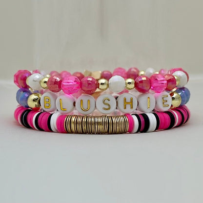 Broadway Stacks POTUS collection. 3 stretch bracelets included in Stack. Pinks, white, blue, golds and black colored beads. Letter beads that spell show quotes. Broadway Stacks gold star logo bead on back.