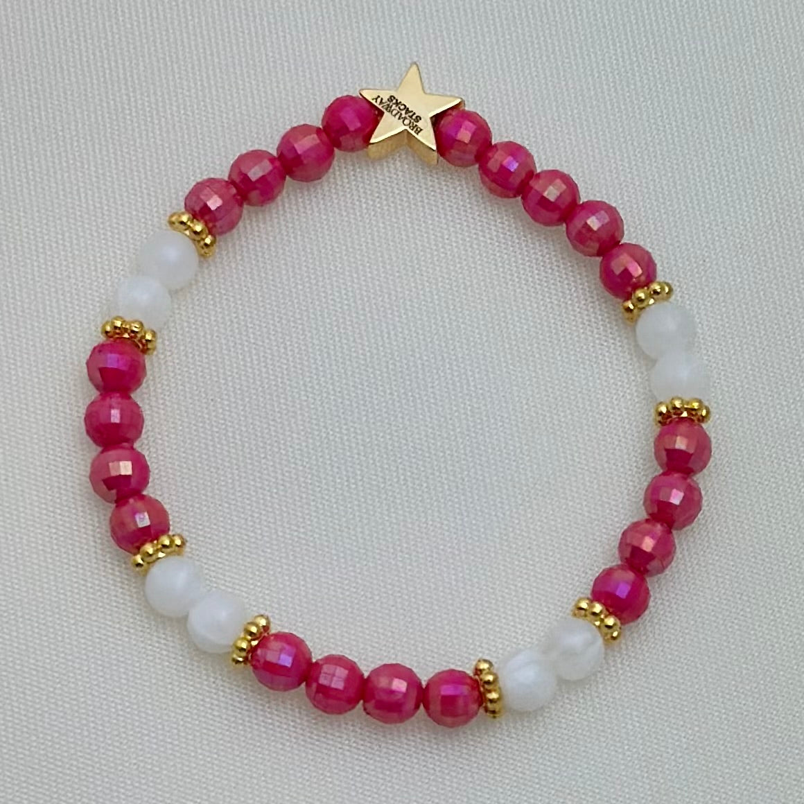 Broadway Stacks POTUS collection. 3 stretch bracelets included in Stack. Pinks, white, blue, golds and black colored beads. Letter beads that spell show quotes. Broadway Stacks gold star logo bead on back.