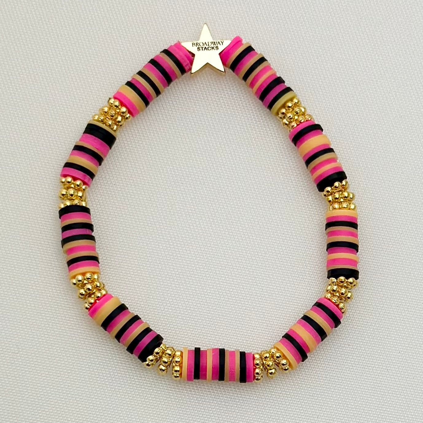 Broadway Stacks De Bois Band collection. 3 stretch bracelets included in Stack. Pinks, golds and black colored beads. Letter beads that spell Show Me Love. Broadway Stacks gold star logo bead on back.