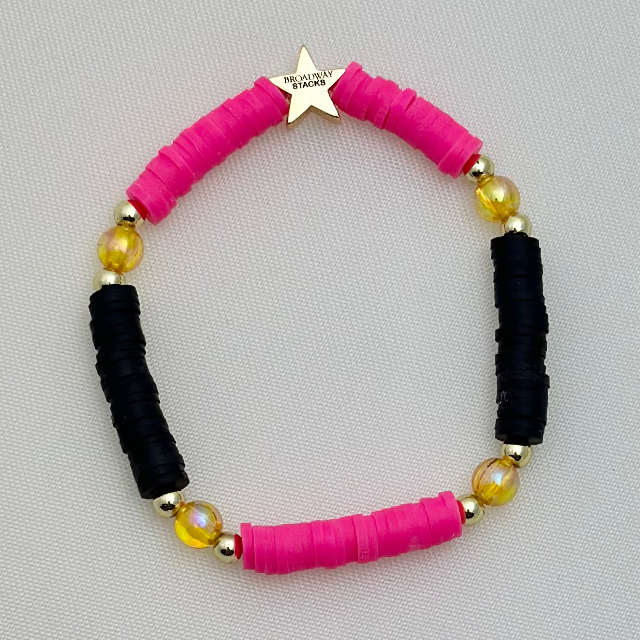 Broadway Stacks De Bois Band collection. 3 stretch bracelets included in Stack. Pinks, golds and black colored beads. Letter beads that spell One More Try. Broadway Stacks gold star logo bead on back.