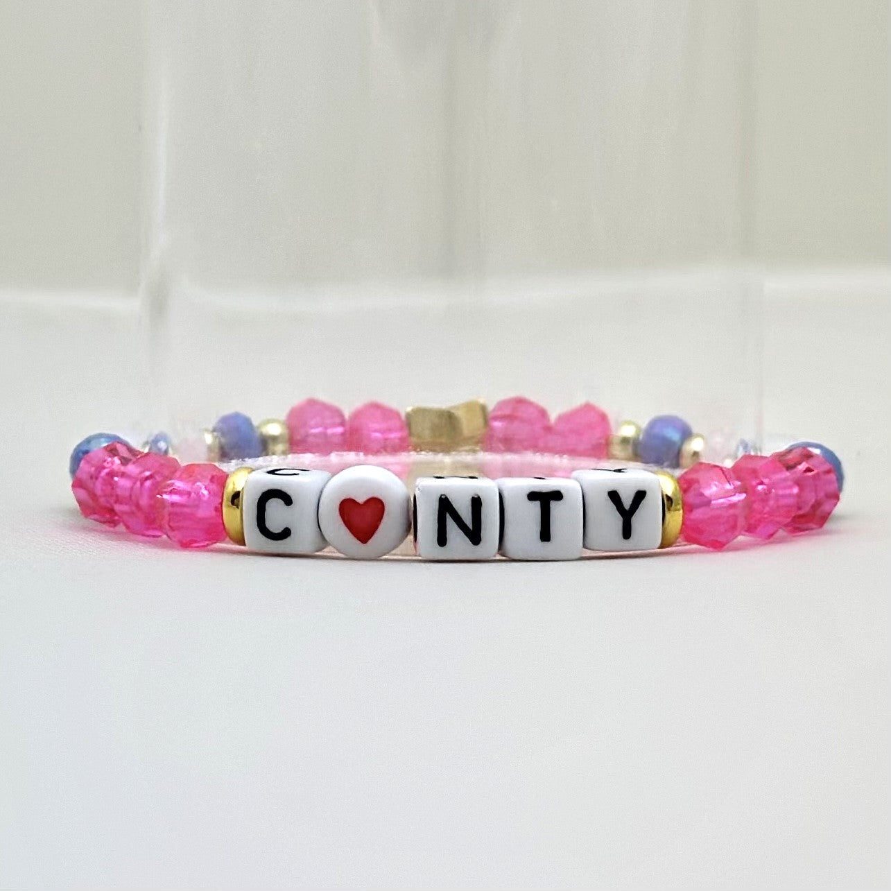 Broadway Stacks POTUS collection. 3 stretch bracelets included in Stack. Pinks, white, blue, golds and black colored beads. Letter beads that spell show quotes. Broadway Stacks gold star logo bead on back.