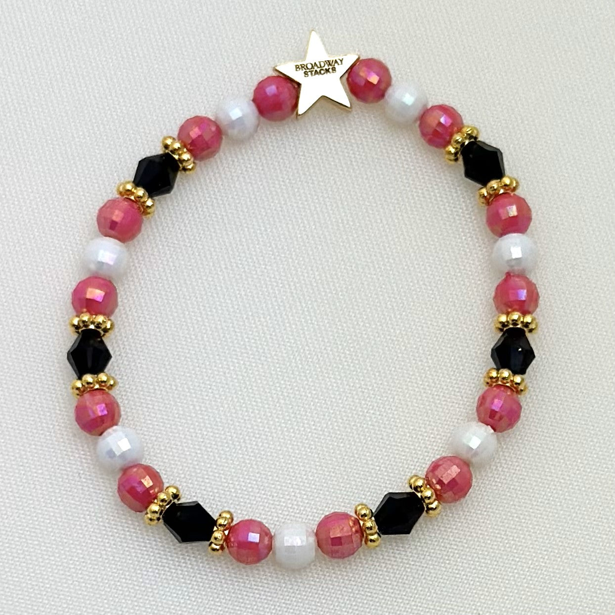 Broadway Stacks POTUS collection. 3 stretch bracelets included in Stack. Pinks, white, blue, golds and black colored beads. Letter beads that spell show quotes. Broadway Stacks gold star logo bead on back.