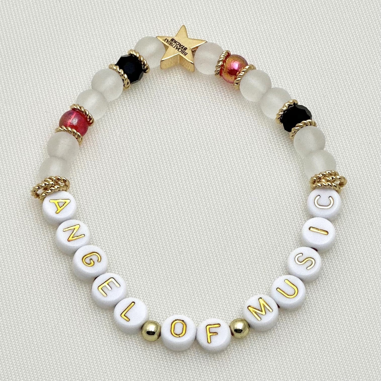 Broadway Stacks Phantom collection. 3 stretch bracelets included in Stack. Red, black, white and gold colored beads. Letter beads that spell Angel Of Music.