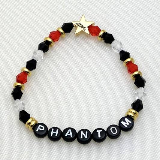 Broadway Stacks MASK collection. 3 stretch bracelets included in Stack. Red, white, gold and black colored beads. Letter beads that spell show quotes. Broadway Stacks gold star logo bead on back.