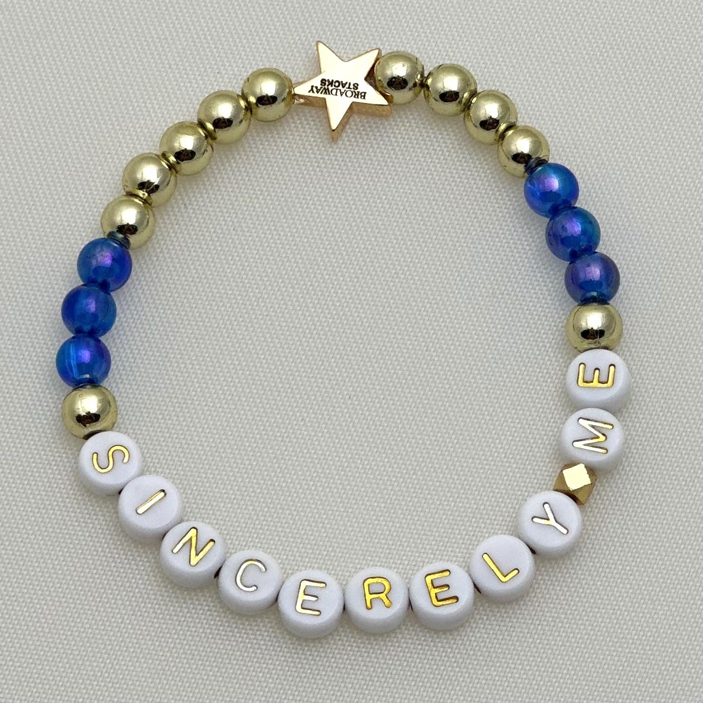 Broadway Stacks SKY collection. 3 stretch bracelets included in Stack. Blues, white, clear, gold and black colored beads. Letter beads that spell show quotes. Broadway Stacks gold star logo bead on back.