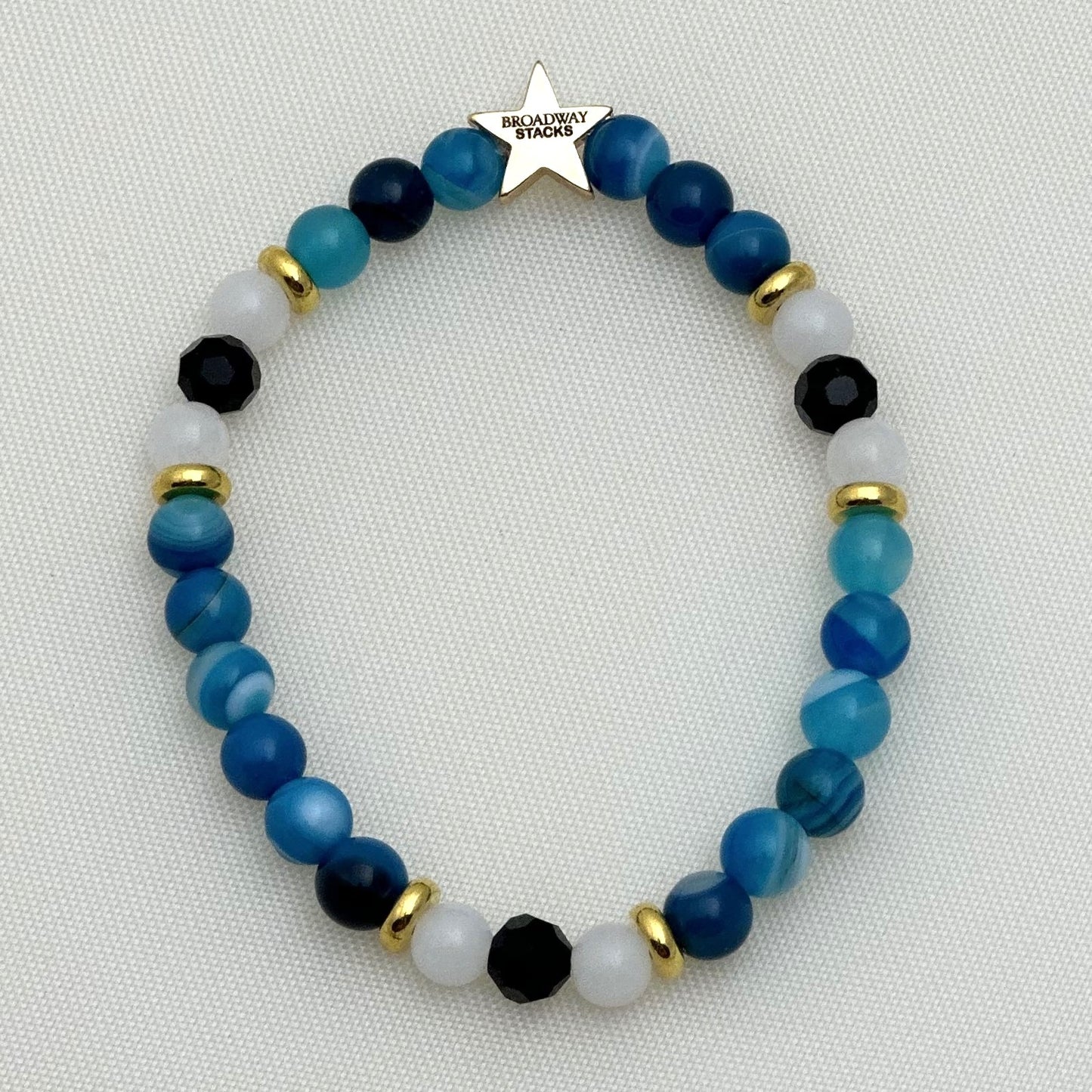 Broadway Stacks SKY collection. 3 stretch bracelets included in Stack. Blues, white, clear, gold and black colored beads. Letter beads that spell show quotes. Broadway Stacks gold star logo bead on back.