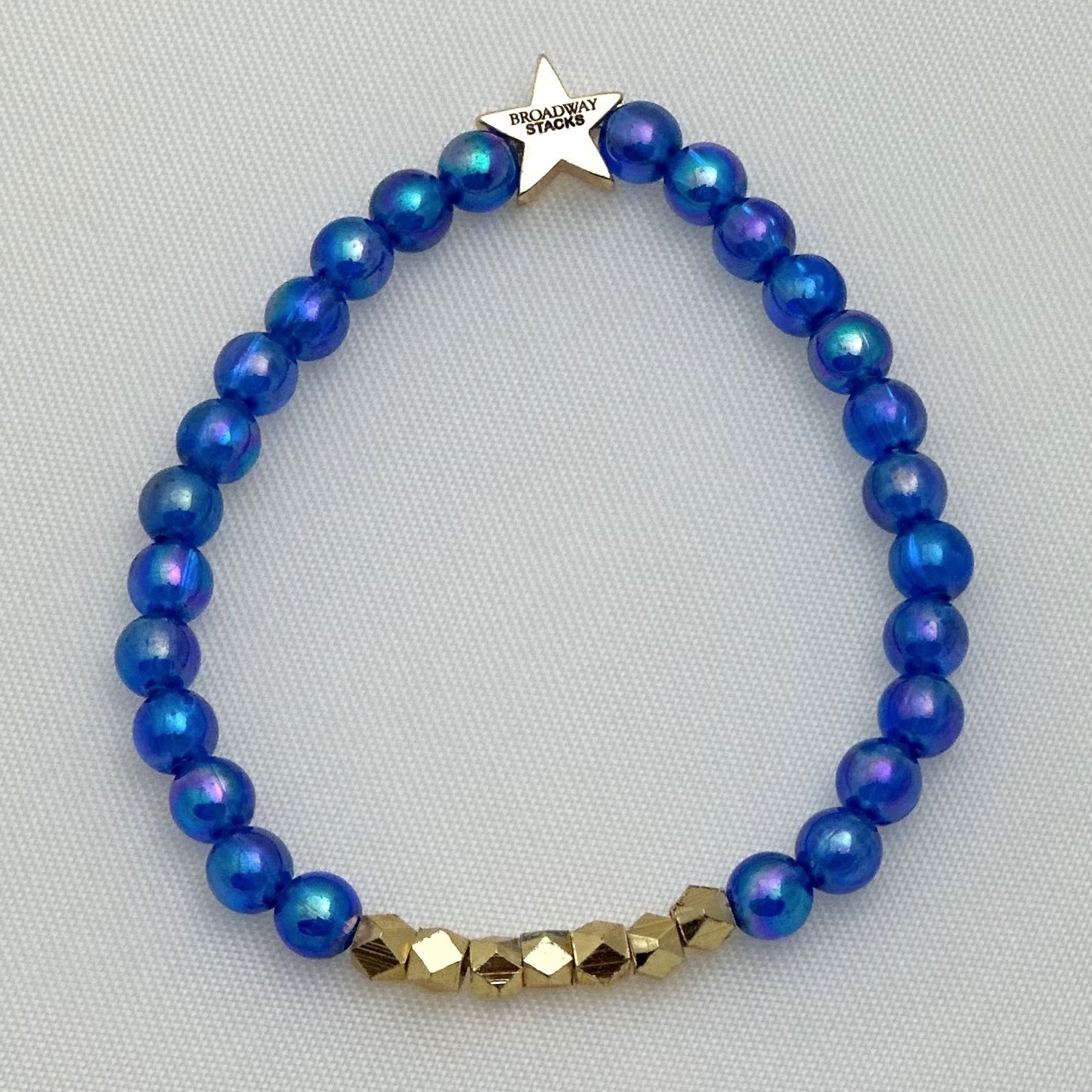 Broadway Stacks SKY collection. 3 stretch bracelets included in Stack. Blues, white, clear, gold and black colored beads. Letter beads that spell show quotes. Broadway Stacks gold star logo bead on back.