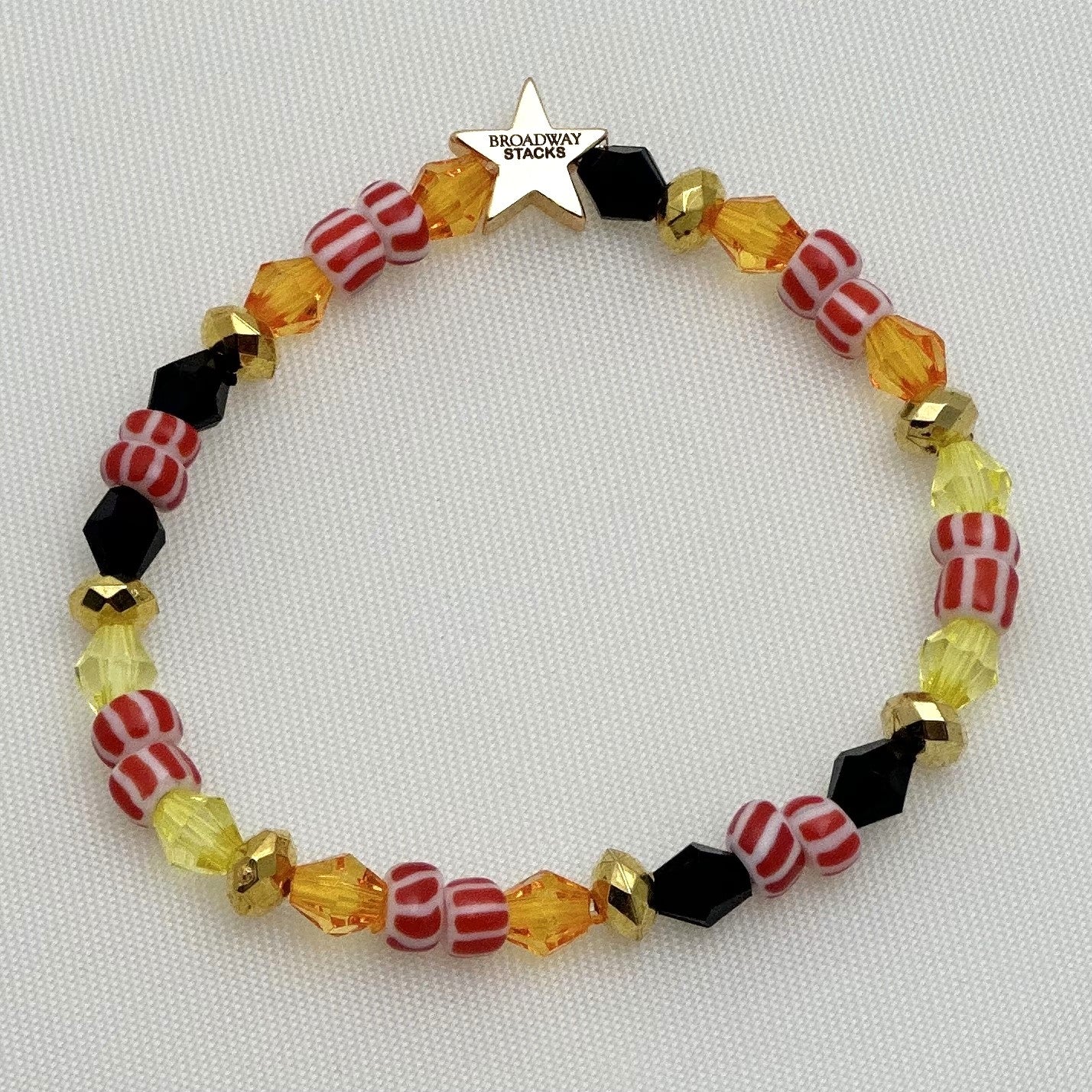 Broadway Stacks SAFARI collection. 3 stretch bracelets included in Stack. Reds, oranges, yellows, black, gold and animal print colored beads. Letter beads that spell show quotes. Broadway Stacks gold star logo bead on back.