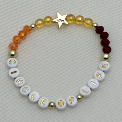 Broadway Stacks SAFARI collection. 3 stretch bracelets included in Stack. Reds, oranges, yellows, black, gold and animal print colored beads. Letter beads that spell show quotes. Broadway Stacks gold star logo bead on back.