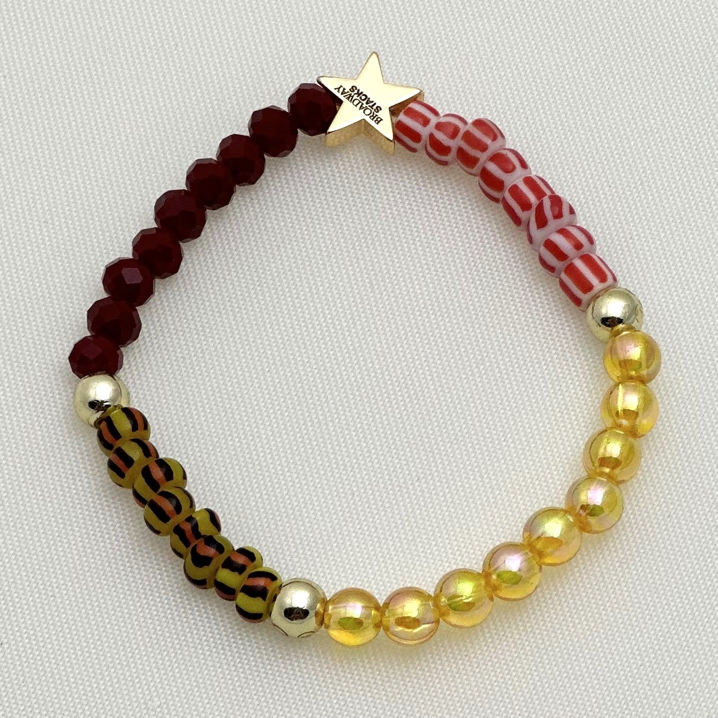 Broadway Stacks SAFARI collection. 3 stretch bracelets included in Stack. Reds, oranges, yellows, black, gold and animal print colored beads. Letter beads that spell show quotes. Broadway Stacks gold star logo bead on back.