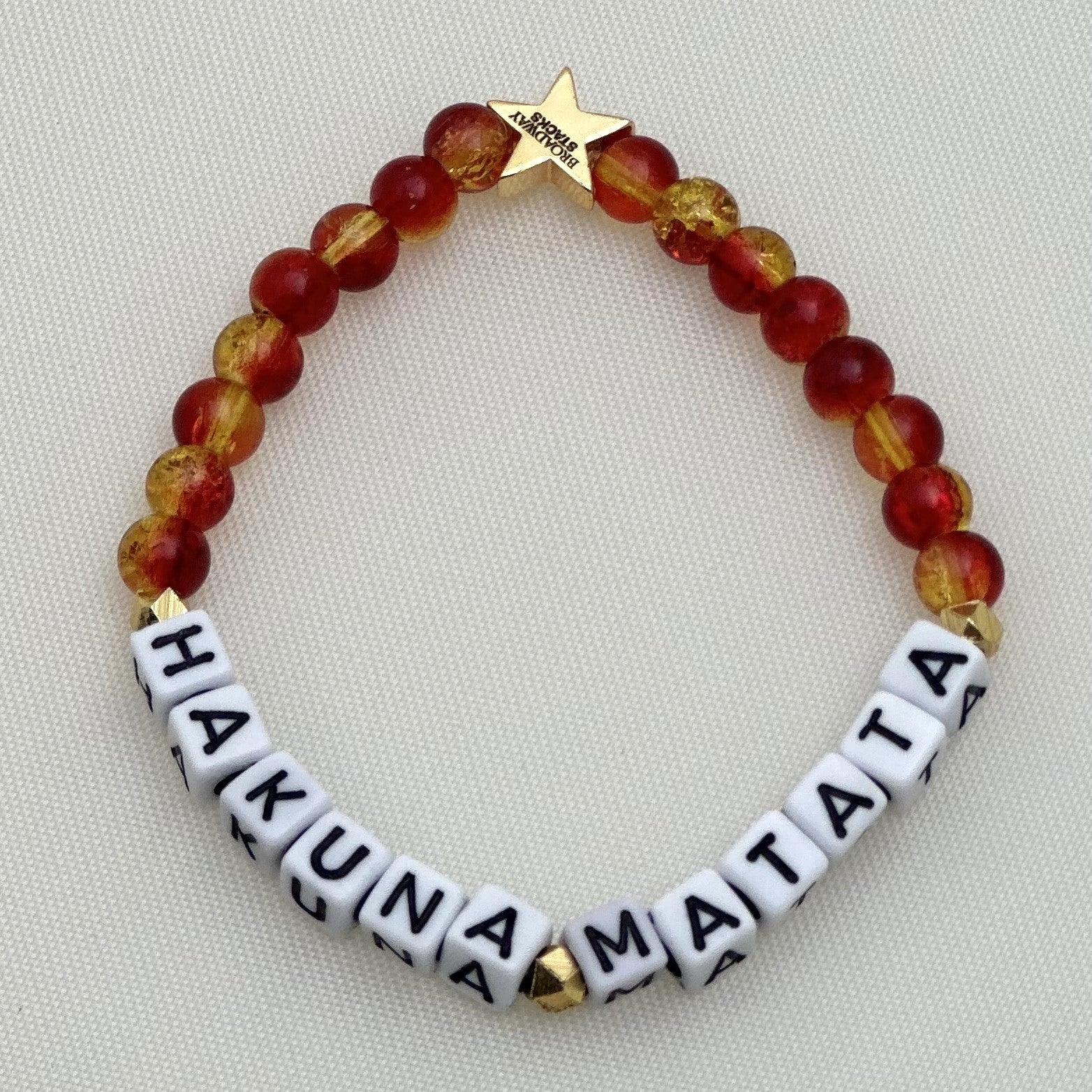 Broadway Stacks SAFARI collection. 3 stretch bracelets included in Stack. Reds, oranges, yellows, black, gold and animal print colored beads. Letter beads that spell show quotes. Broadway Stacks gold star logo bead on back.