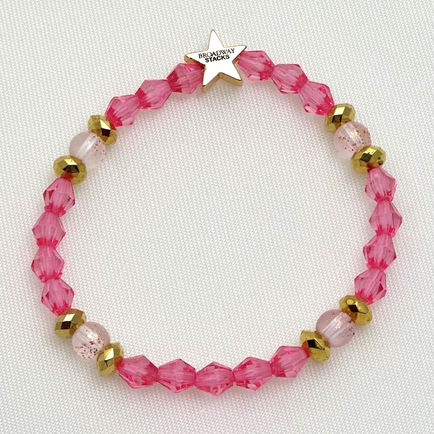 Broadway Stacks KEEP IT POSITIVE collection. 3 stretch bracelets included in Stack. Pinks, white, and gold colored beads. Letter beads that spell show quotes. Broadway Stacks gold star logo bead on back.