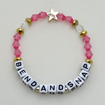 Broadway Stacks KEEP IT POSITIVE collection. 3 stretch bracelets included in Stack. Pinks, white, and gold colored beads. Letter beads that spell show quotes. Broadway Stacks gold star logo bead on back.