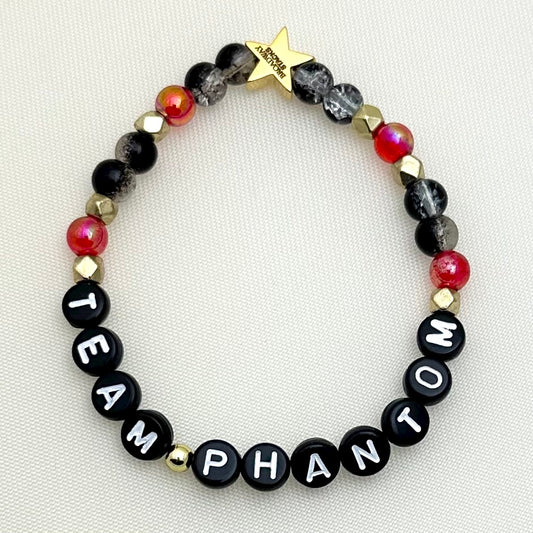 Broadway Stacks MASK collection. Stretch bracelet with red, black,  gold and letter beads. Gold star logo bead.