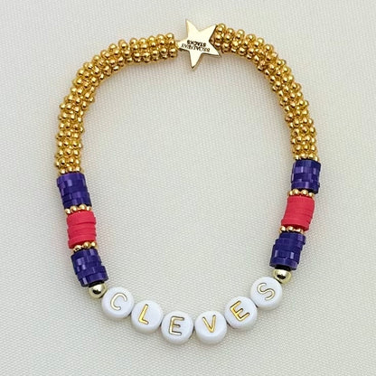 Broadway Stacks QUEEN collection. Stretch bracelets included in Stack. Gold, yellow, green, white, red, pink and blue colored beads. Letter beads that spell each queen. Also Herstory collection. Broadway Stacks gold star logo bead on back.