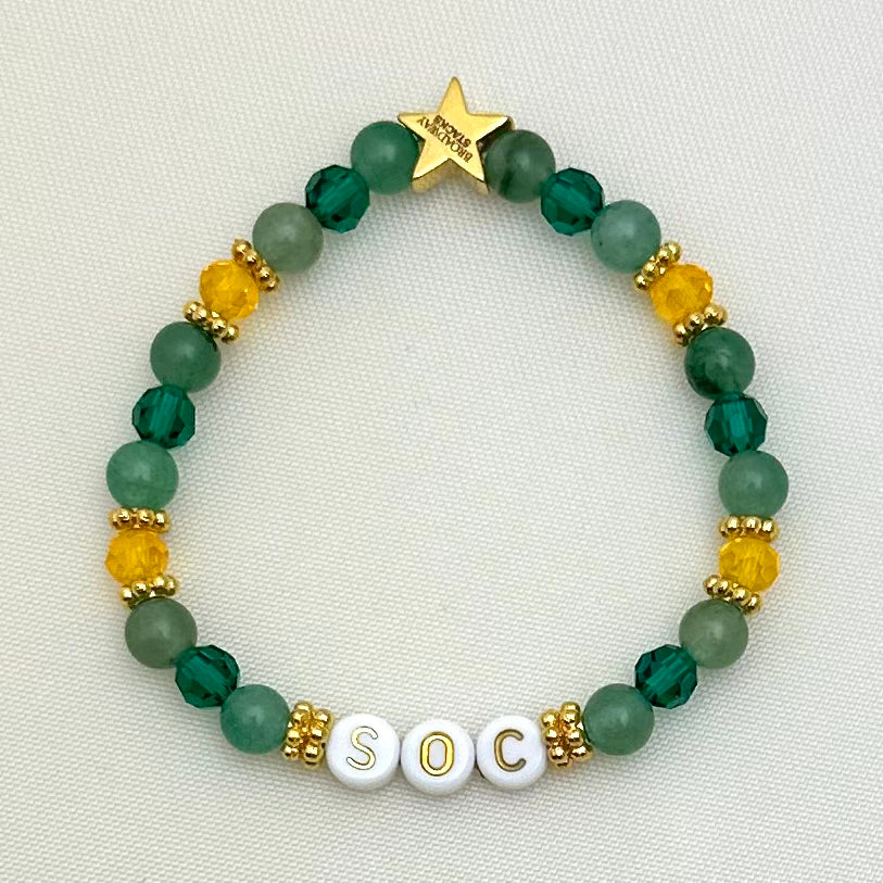 Broadway Stacks STAY GOLD collection. Stretch bracelets included in Stack. Gold, yellow, green and grey colored beads. Letter beads that have show quote or name. Broadway Stacks gold star logo bead on back.