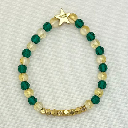 Broadway Stacks STAY GOLD collection. Stretch bracelets included in Stack. Gold, yellow, green and grey colored beads. Letter beads that have show quote or name. Broadway Stacks gold star logo bead on back.