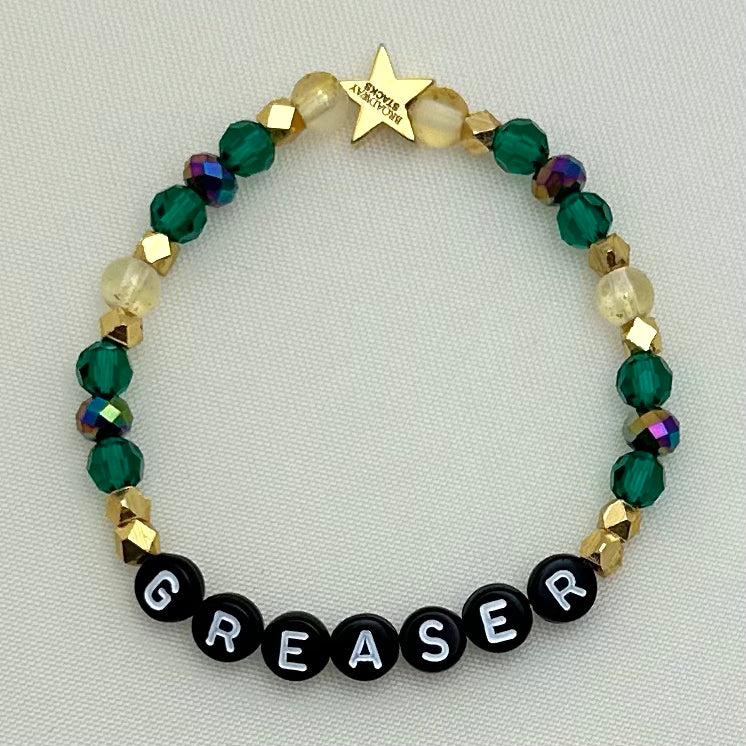 Broadway Stacks STAY GOLD collection. Stretch bracelets included in Stack. Gold, yellow, green and grey colored beads. Letter beads that have show quote or name. Broadway Stacks gold star logo bead on back.