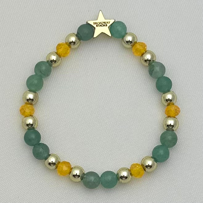 Broadway Stacks STAY GOLD collection. Stretch bracelets included in Stack. Gold, yellow, green and grey colored beads. Letter beads that have show quote or name. Broadway Stacks gold star logo bead on back.