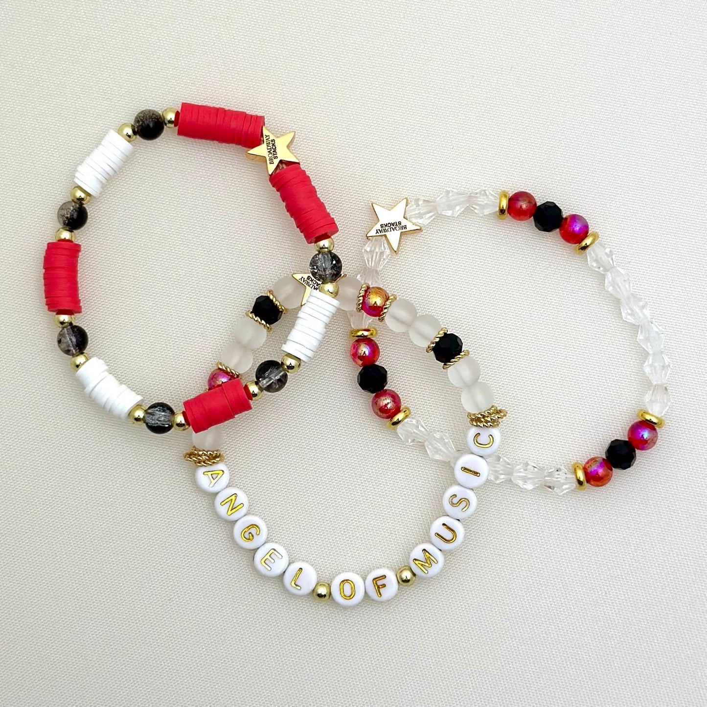 Broadway Stacks Phantom collection. 3 stretch bracelets included in Stack. Red, black, white and gold colored beads. Letter beads that spell Angel Of Music.