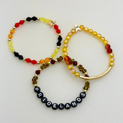 Broadway Stacks SAFARI collection. 3 stretch bracelets included in Stack. Reds, oranges, yellows, black, gold and animal print colored beads. Letter beads that spell show quotes. Broadway Stacks gold star logo bead on back.