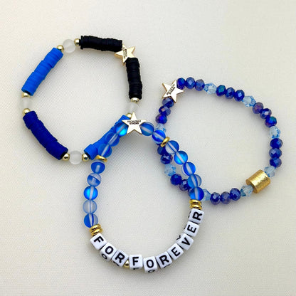 Broadway Stacks SKY collection. 3 stretch bracelets included in Stack. Blues, white, clear, gold and black colored beads. Letter beads that spell show quotes. Broadway Stacks gold star logo bead on back.