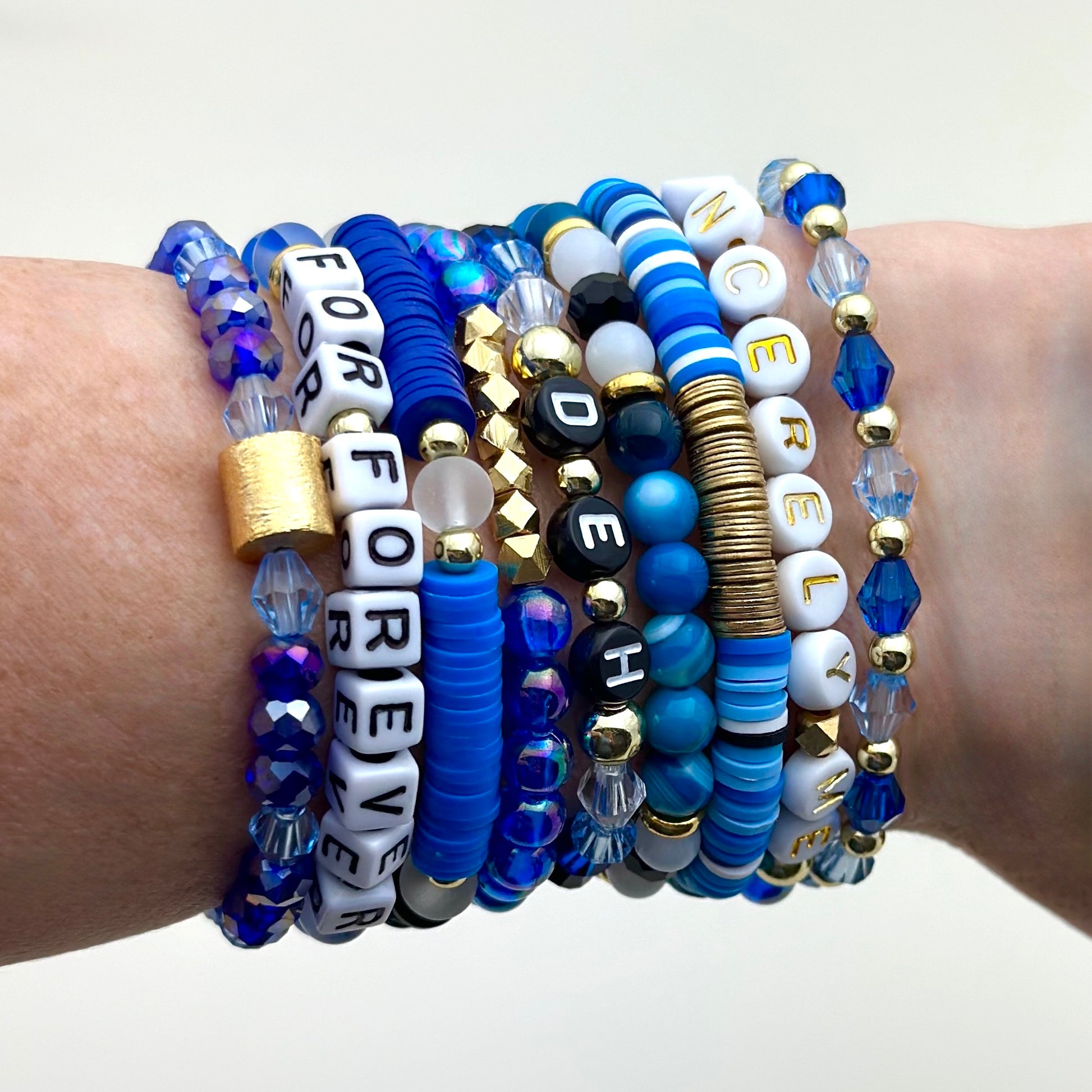 Broadway Stacks SKY collection. 3 stretch bracelets included in Stack. Blues, white, black and gold colored beads. Letter beads that spell DEH.