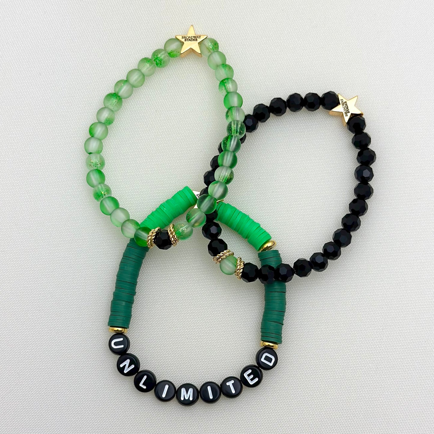 Broadway Stacks Witch collection. 3 stretch bracelets included in Stack. Greens, black and gold colored beads. Letter beads that spell Unlimited.