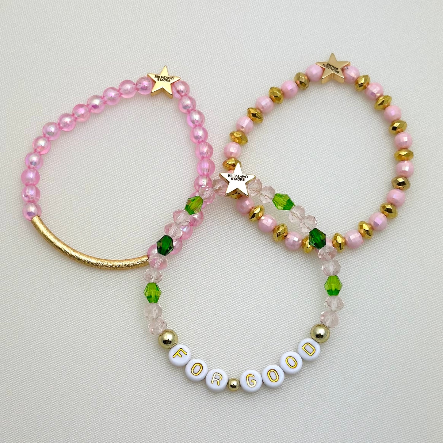 Broadway Stacks Witch collection. 3 stretch bracelets included in Stack. Greens, pinks and gold colored beads. Letter beads that spell For Good.