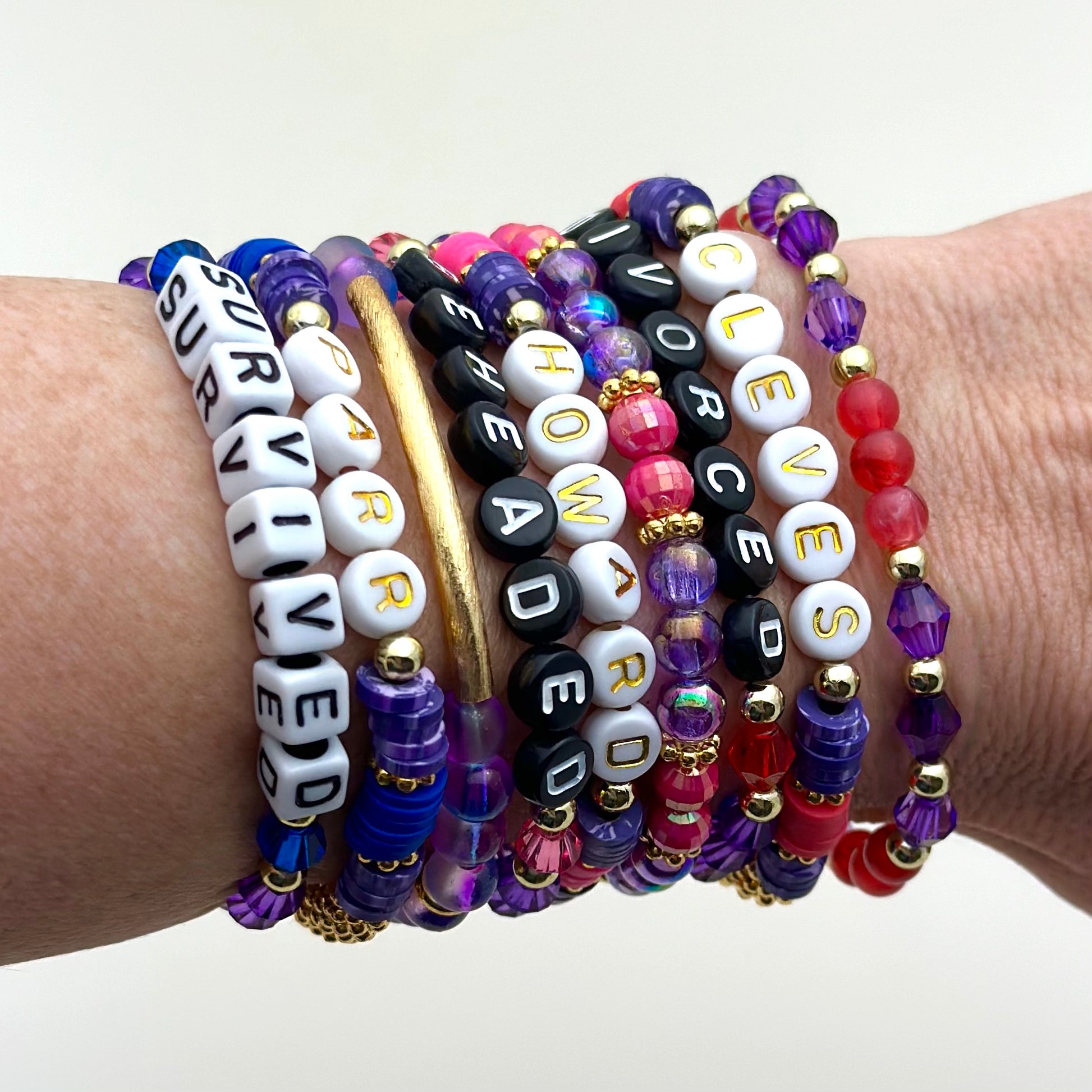 Broadway Stacks QUEEN collection. Stretch bracelets included in Stack. Gold, yellow, green, white, red, pink and blue colored beads. Letter beads that spell each queen. Also Herstory collection. Broadway Stacks gold star logo bead on back.