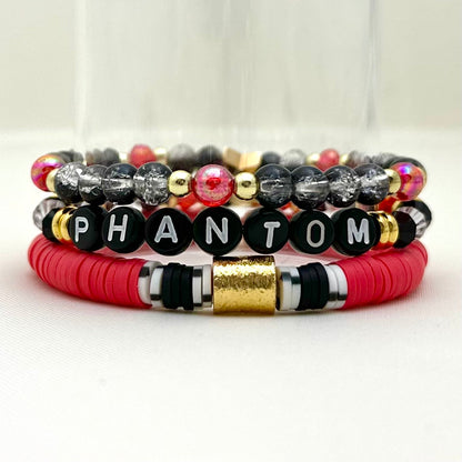 Broadway Stacks MASK collection. 3 stretch bracelets included in Stack. Red, white, gold and black colored beads. Letter beads that spell show quotes. Broadway Stacks gold star logo bead on back.