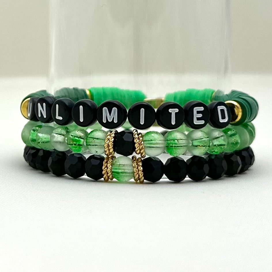 Broadway Stacks Witch collection. 3 stretch bracelets included in Stack. Greens, black and gold colored beads. Letter beads that spell Unlimited.