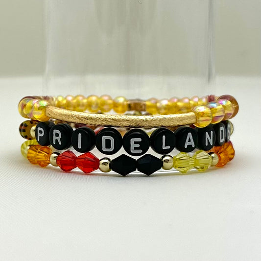 Broadway Stacks SAFARI collection. 3 stretch bracelets included in Stack. Dark reds, yellow, orange, white, black and gold colored beads. Animal print beads as well. Letter beads that spell Pridelands.