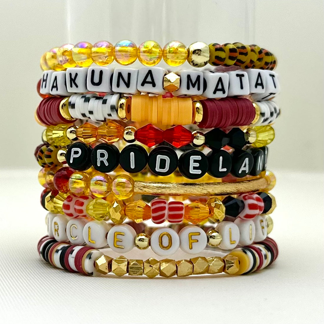 Broadway Stacks SAFARI collection. 3 stretch bracelets included in Stack. Dark reds, yellow, orange, white, black and gold colored beads. Animal print beads as well. Letter beads that spell Hakuna Matata.