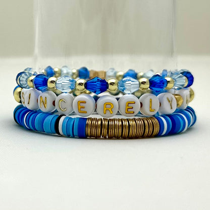 Broadway Stacks SKY collection. 3 stretch bracelets included in Stack. Blues, white, black and gold colored beads. Letter beads that spell Sincerely Me.