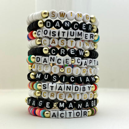 Broadway Stacks SPOTLIGHT Collection. Handcrafted beaded elastic-stretch bracelet with letter beads. Available in many varieties of theatre positions like actor, singer, dancer, director, stage manager, understudy, bway lover, crew, musician, etc. Gold color accents. Available in black, white and mulit-color. Broadway Stacks gold star logo bead on back.