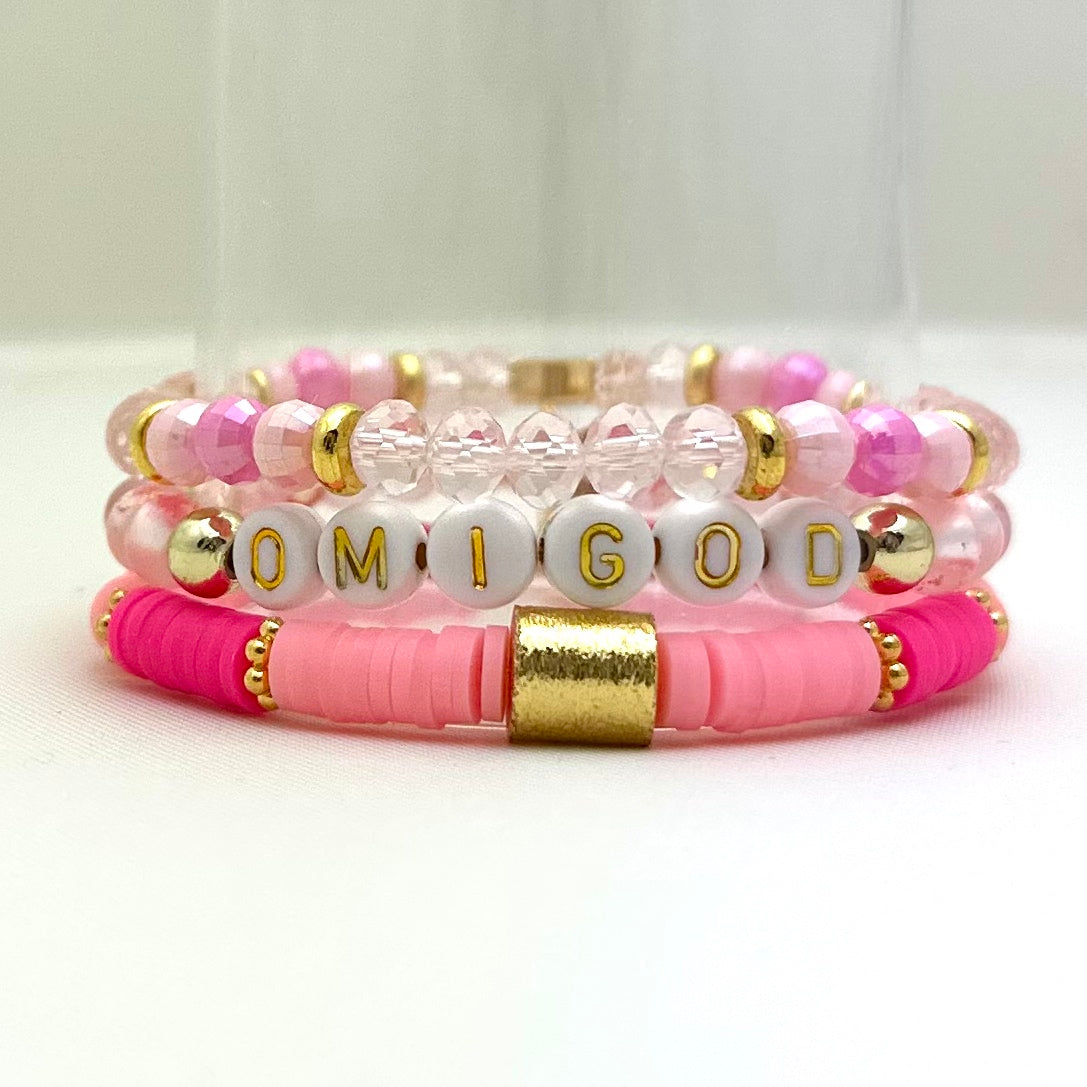 Broadway Stacks KEEP IT POSITIVE collection. 3 stretch bracelets included in Stack. Pinks, white, and gold colored beads. Letter beads that spell show quotes. Broadway Stacks gold star logo bead on back.