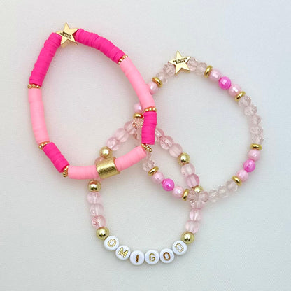 Broadway Stacks KEEP IT POSITIVE collection. 3 stretch bracelets included in Stack. Pinks, white, and gold colored beads. Letter beads that spell show quotes. Broadway Stacks gold star logo bead on back.