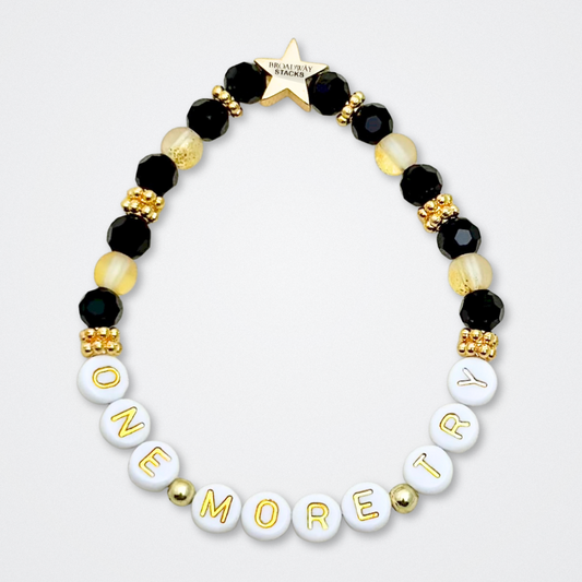Broadway Stacks De Bois Band collection. 3 stretch bracelets included in Stack. Pinks, golds and black colored beads. Letter beads that spell quotes. Broadway Stacks gold star logo bead to remind you that you shine. & Juliet fans.