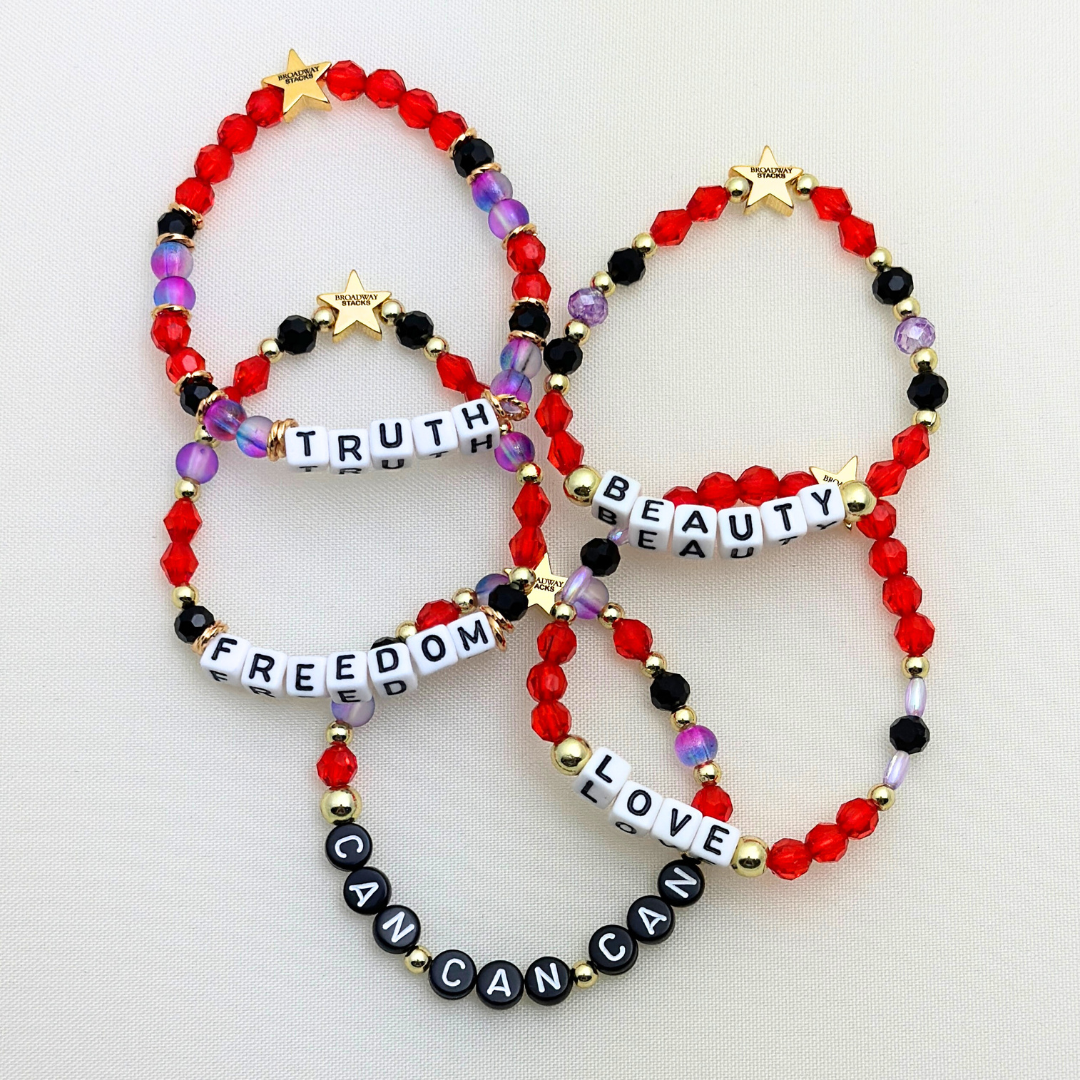 Broadway Stacks RED LIGHT Collection. 5 stretch bracelets included in Stack. Red, purple, black and gold colored beads. Letter beads that spell quotes. Gold star logo bead to remind you that you shine. Moulin Rouge fans. 