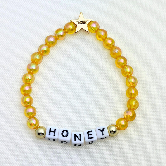 Broadway Stacks HONEY Collection. 3 stretch bracelets included in Stack. Red, yellow and gold colored beads. Letter beads that spell quotes. Gold star logo bead to remind you that you shine.