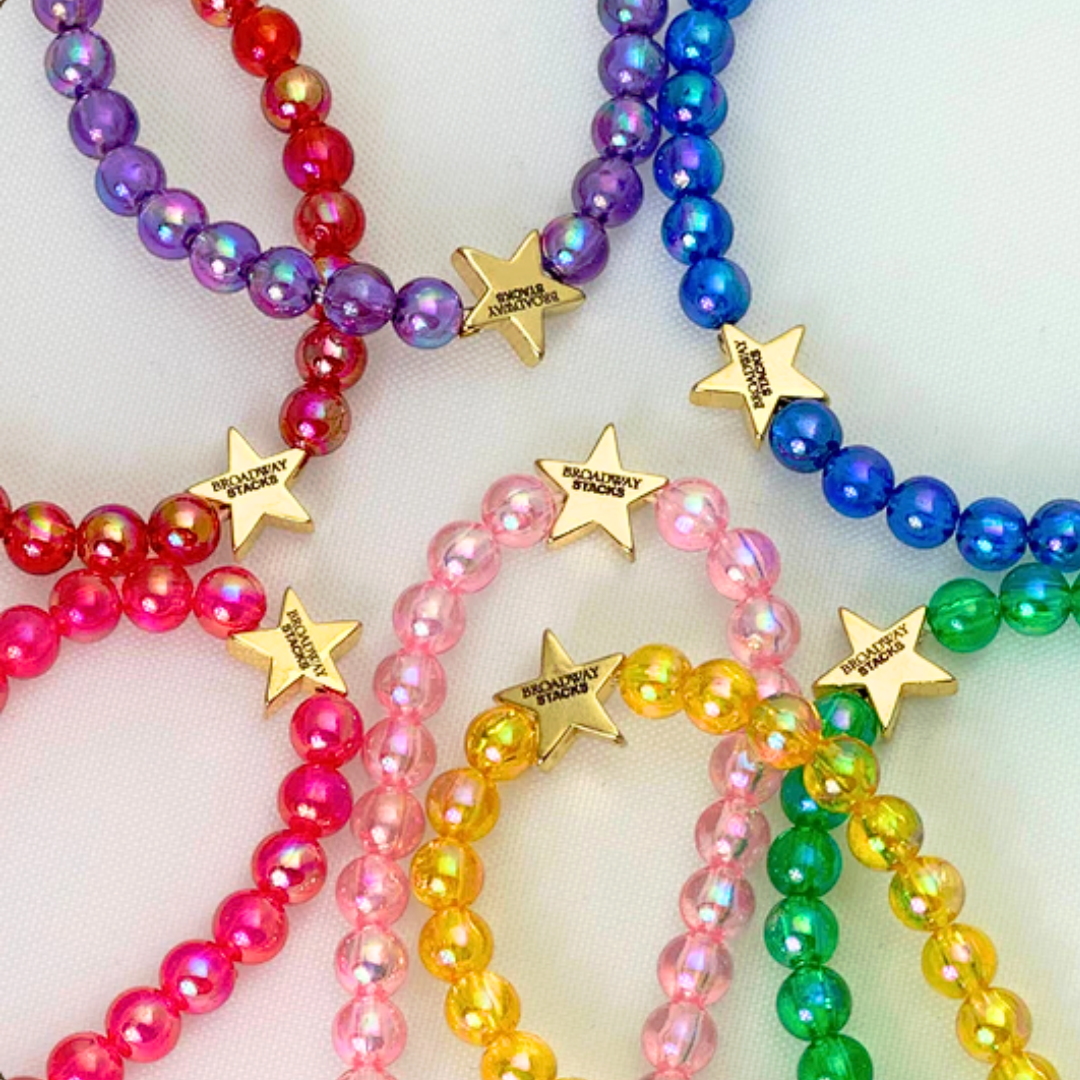 Broadway Stacks SPOTLIGHT Collection. Handcrafted beaded elastic-stretch bracelet with letter beads. Available in many varieties of theatre positions like actor, singer, dancer, director, stage manager, understudy, bway lover, crew, musician, etc. Gold color accents. Available in 7 colors. Broadway Stacks gold star logo bead on back.