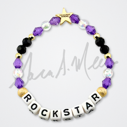 Broadway Stacks Special Edition Sara Mearns ROCKSTAR Bracelet Collection. 5 stretch bracelets included in Stack. Purple, clear, white, black and gold colored beads. Letter beads that spell quotes. Gold star logo bead to remind you that you shine. Sara Mearns and Ballet fans.