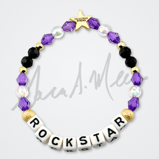 Broadway Stacks Special Edition Sara Mearns ROCKSTAR Bracelet Collection. 5 stretch bracelets included in Stack. Purple, clear, white, black and gold colored beads. Letter beads that spell quotes. Gold star logo bead to remind you that you shine. Sara Mearns and Ballet fans.