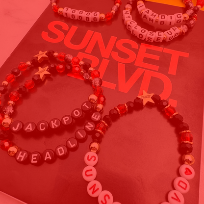 Broadway Stacks CLOSE-UP Collection. 6 stretch bracelets included in Stack. Red, black and gold colored beads. Letter beads that spell quotes. Gold star logo bead to remind you that you shine. Sunset Blvd fans. 